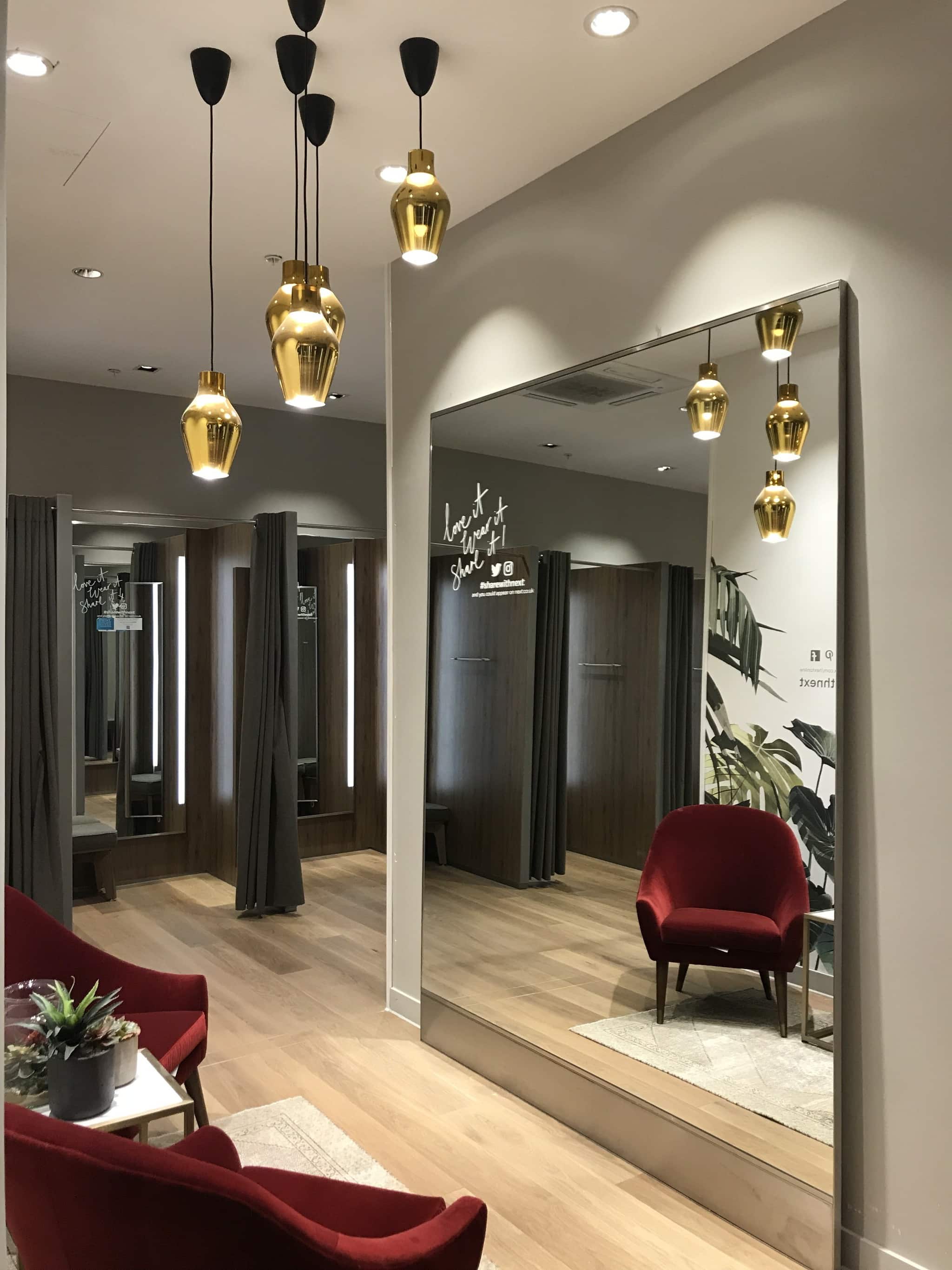 Retail dressing room with large floor length mirrors and hanging pendant lighting